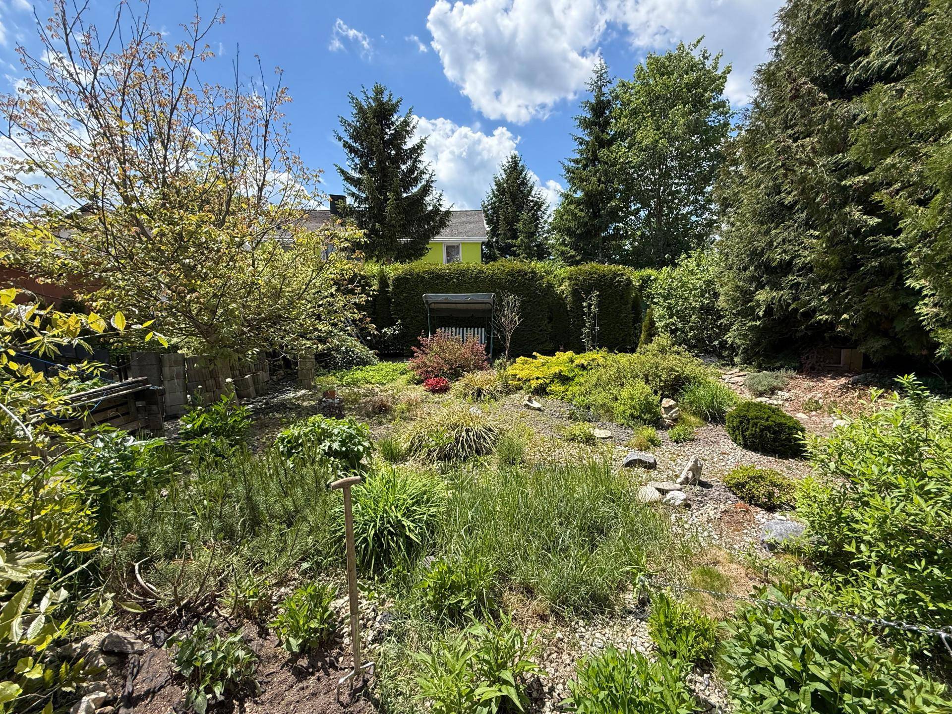 Weitläufiger Garten mit vielfältiger Bepflanzung, Sträuchern und einem gepflegten Rasen.