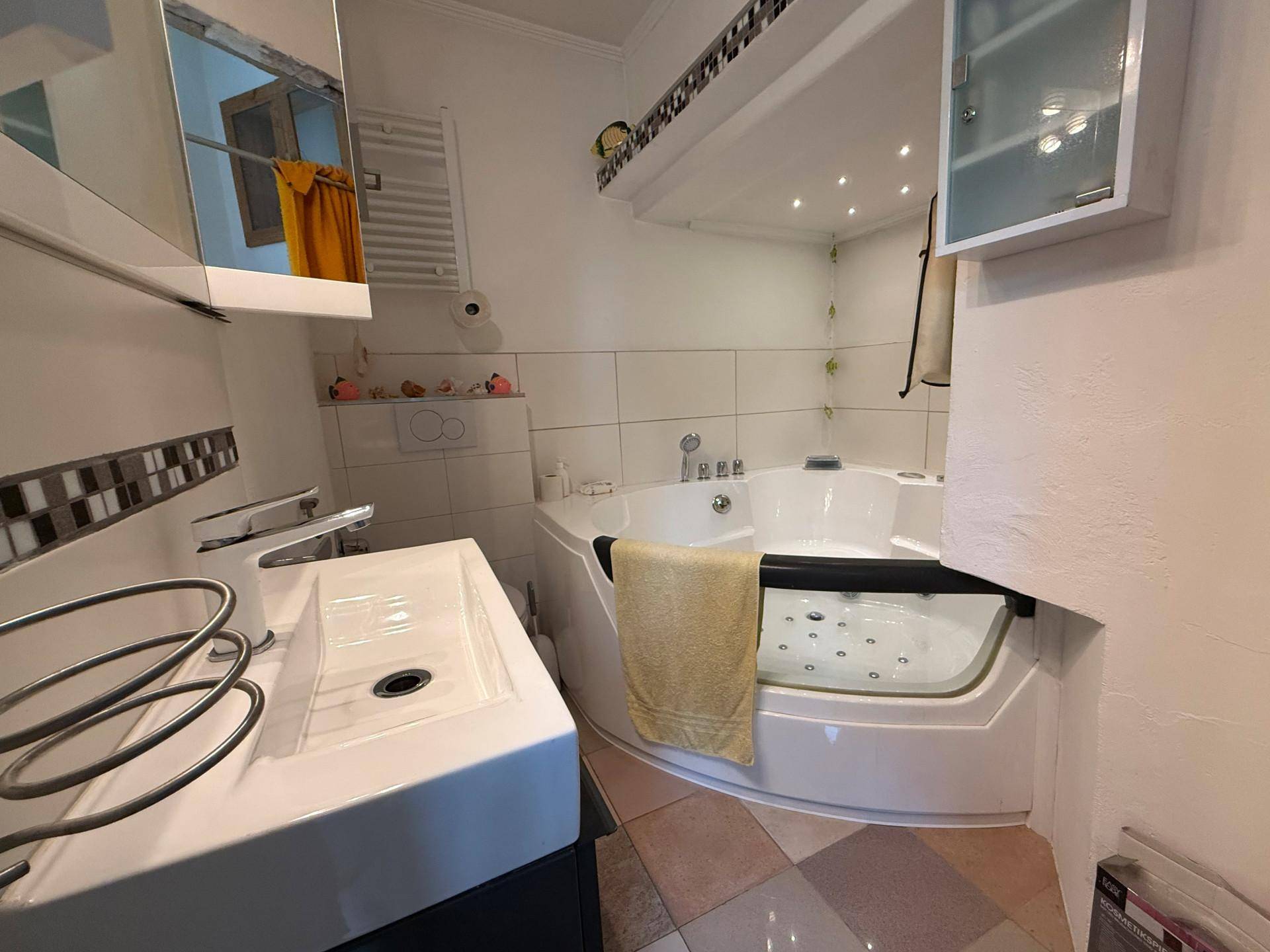 Modernes Badezimmer mit Eckbadewanne, Whirlpool-Funktion und weiß gefliesten Wänden.