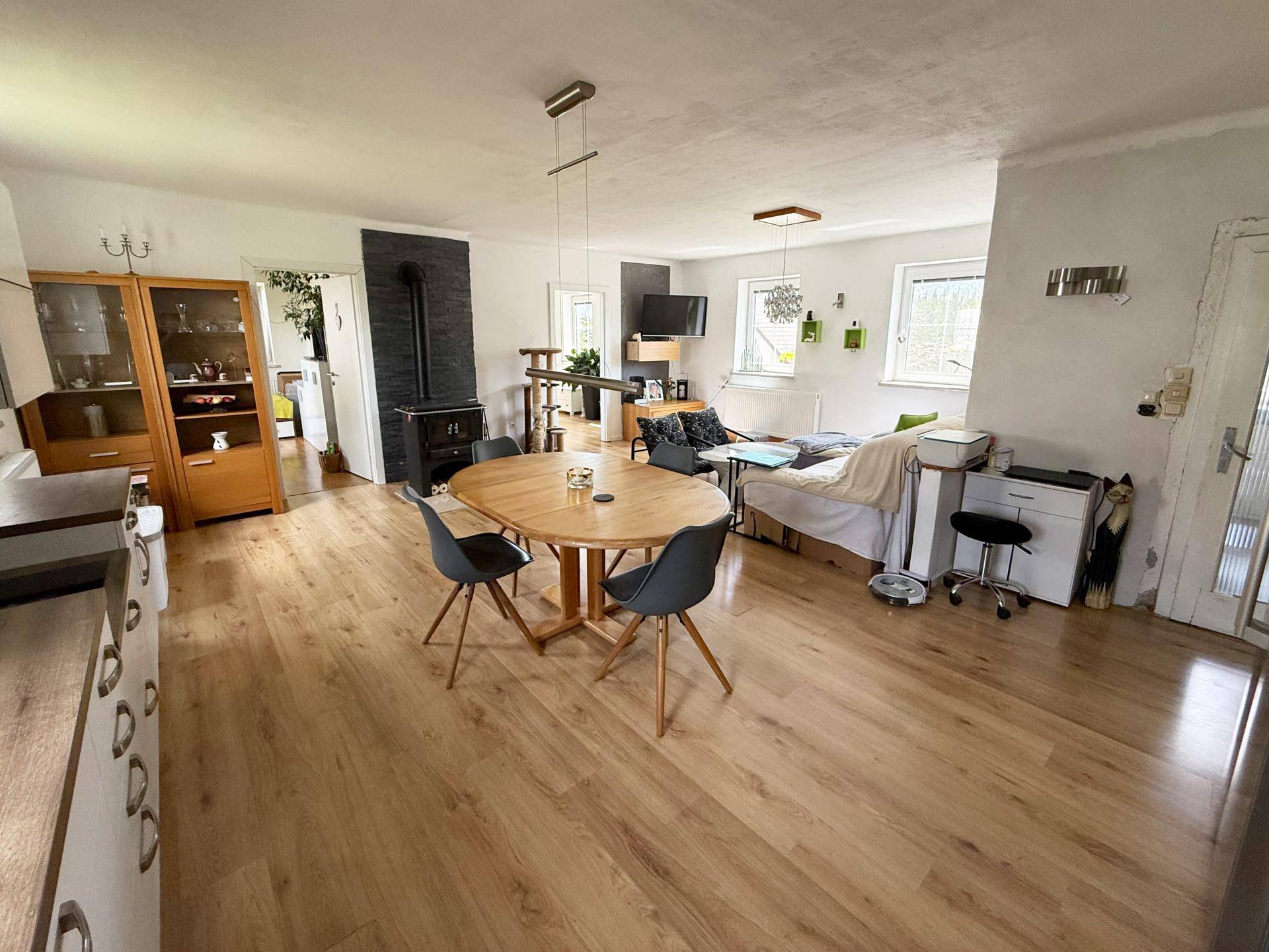 Geräumiger offener Wohn- und Essbereich mit Holzboden und gemütlichem Holzofen.
