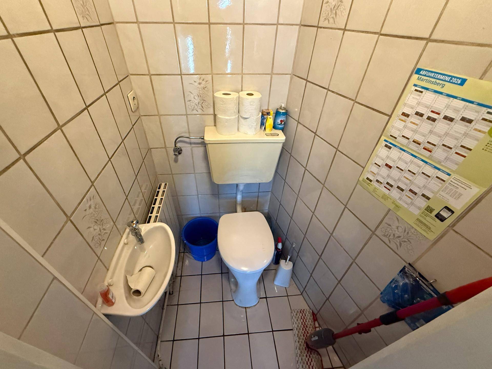 Kleines Gäste-WC mit Toilette, Waschbecken und hellen Fliesen.