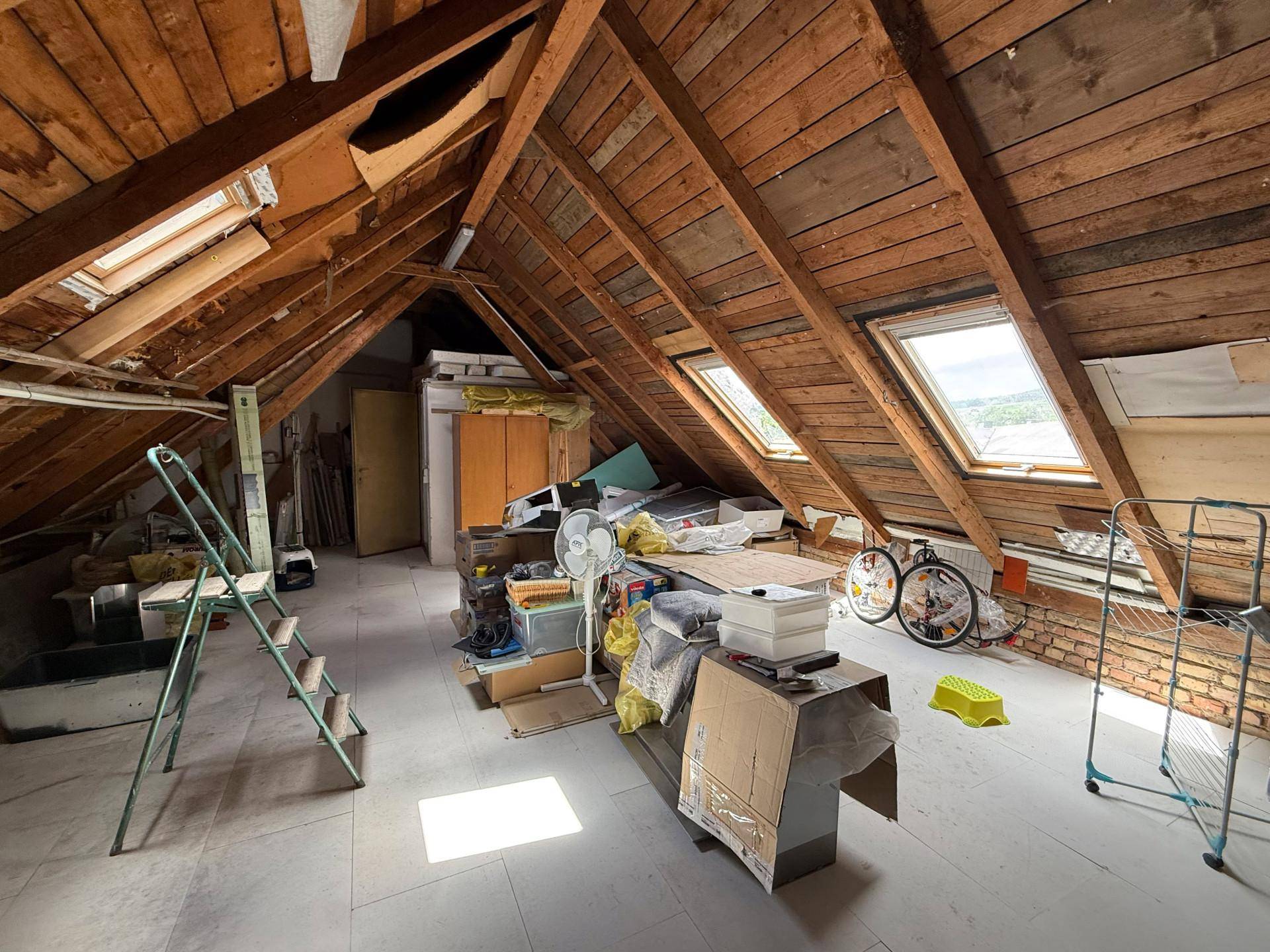 Dachboden mit Holzbalken, mehreren Dachfenstern und viel Platz für Lagerung.