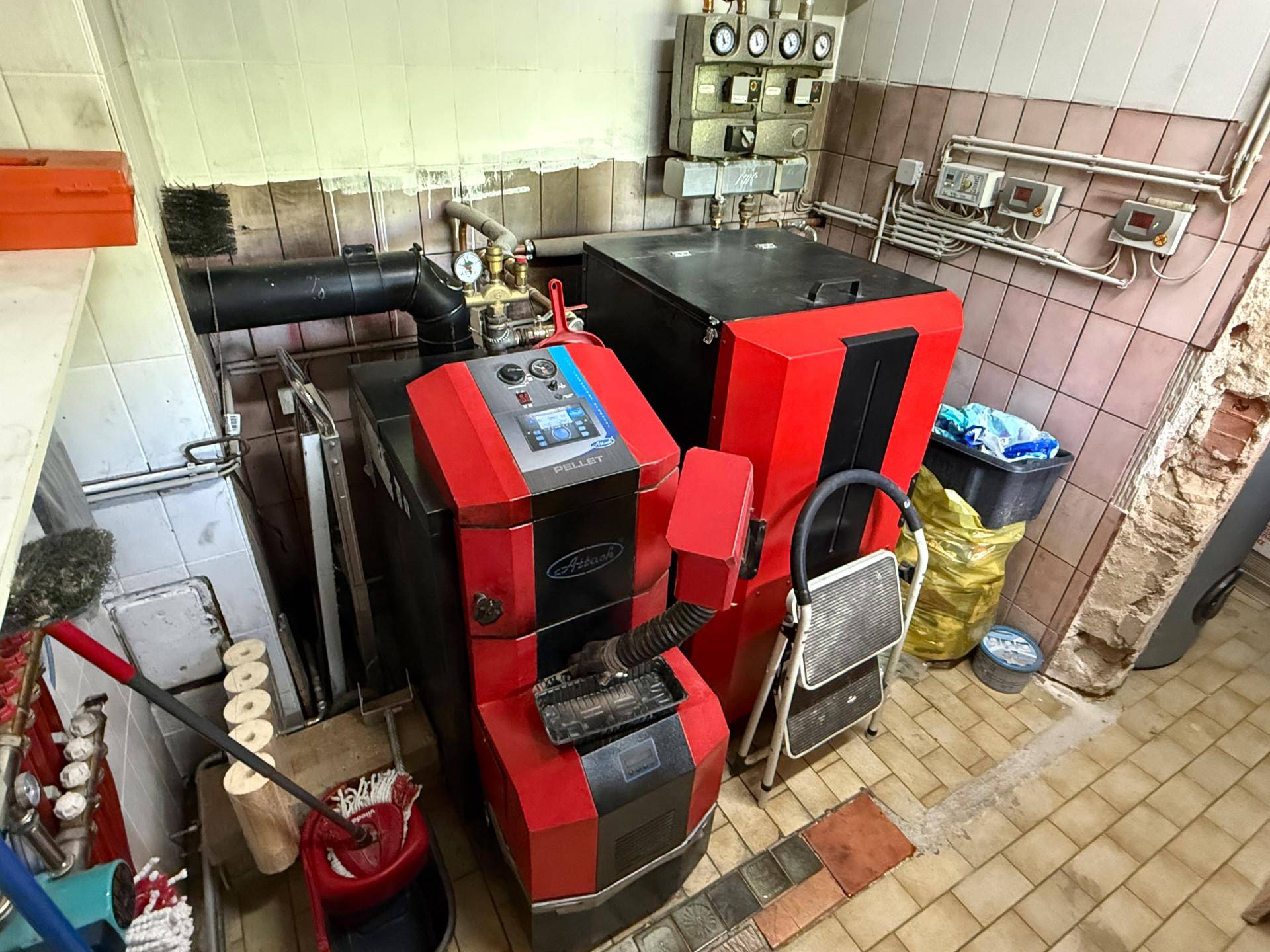 Heizungsraum im Keller mit moderner Pelletheizungsanlage und technischen Installationen.