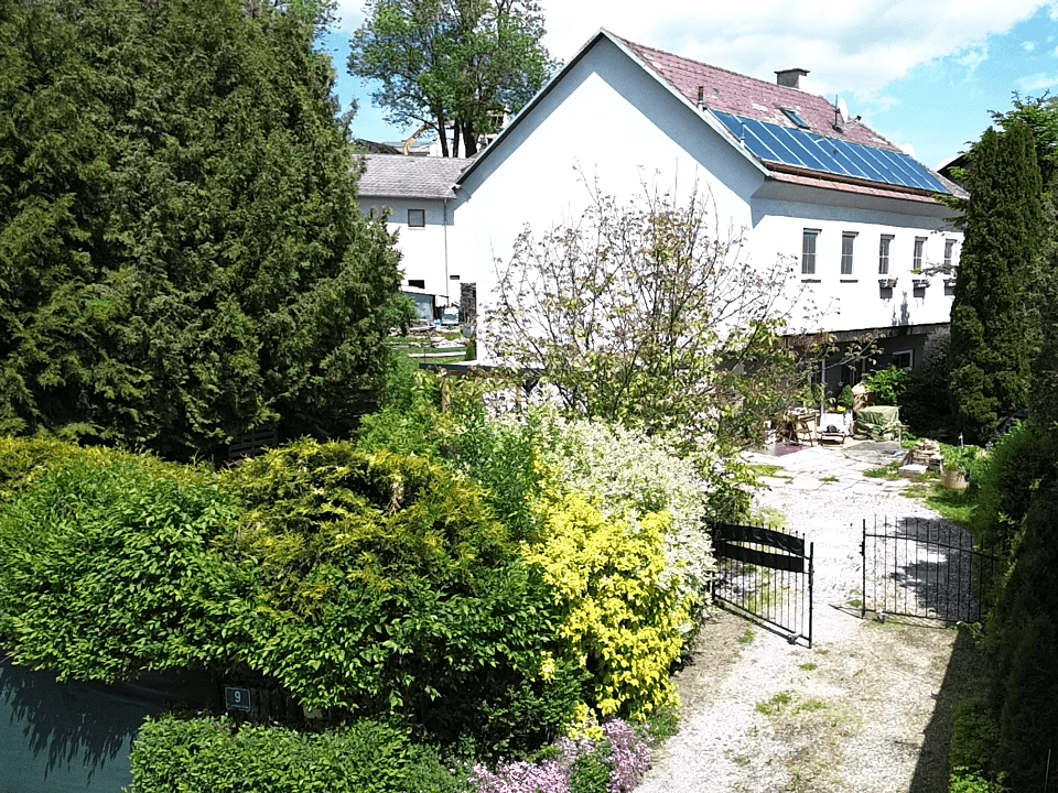 Luftaufnahme des Hauses mit Garten, Zufahrt und Photovoltaikanlage auf dem Dach.