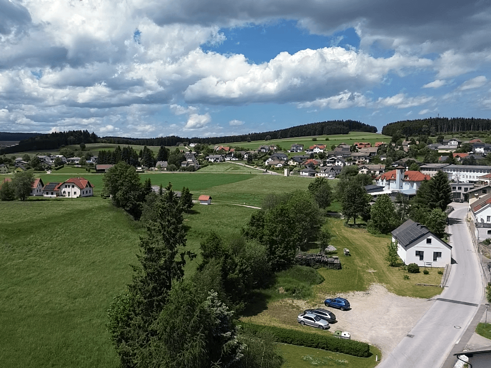 Weitläufiger Blick über die ländliche Umgebung mit Häusern und grünen Feldern.