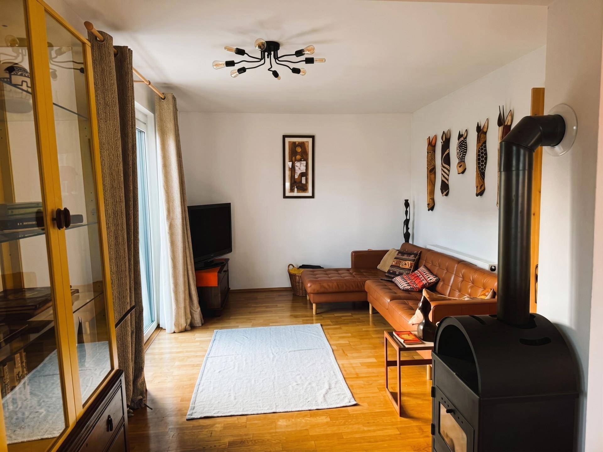 Gemütliches Wohnzimmer mit Ledersofa, Holzboden und einem modernen Holzofen.