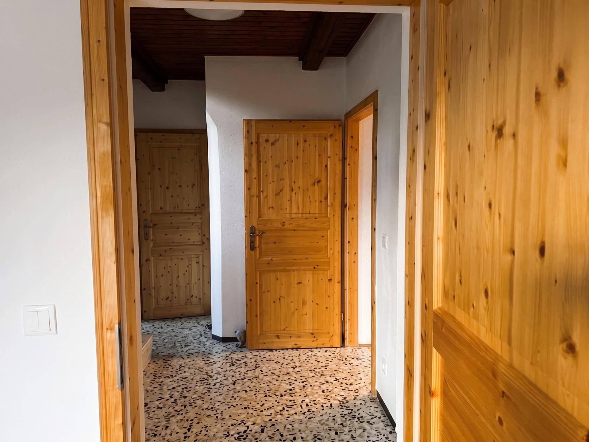 Flur mit Holztüren und Terrazzoboden, der zu weiteren Räumen führt.