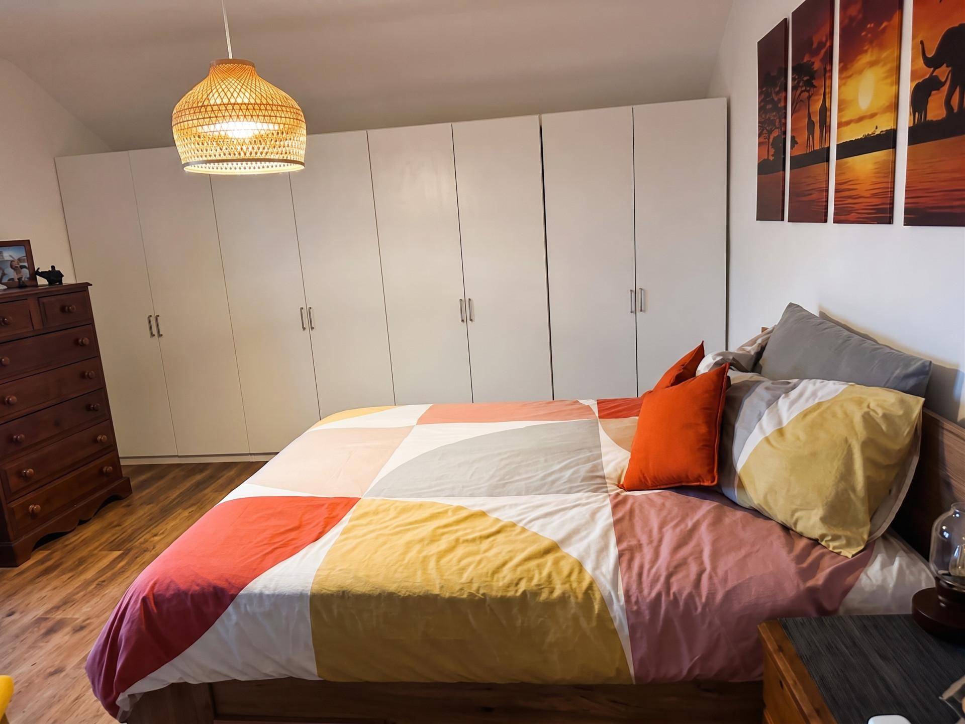 Schlafzimmer mit großem Bett, Einbauschränken und Holzboden, hell und geräumig.