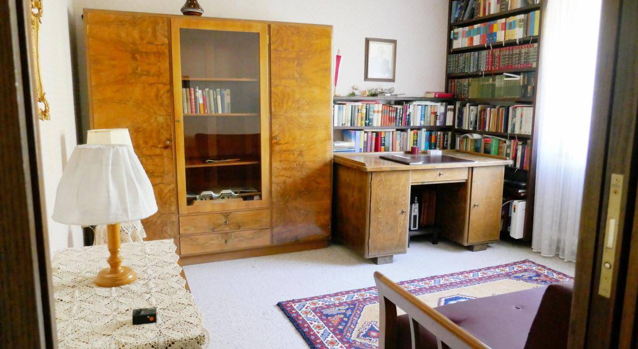 Helles Arbeitszimmer mit Holzschreibtisch, Bücherregalen und Teppichboden, ideal für konzentriertes Arbeiten.