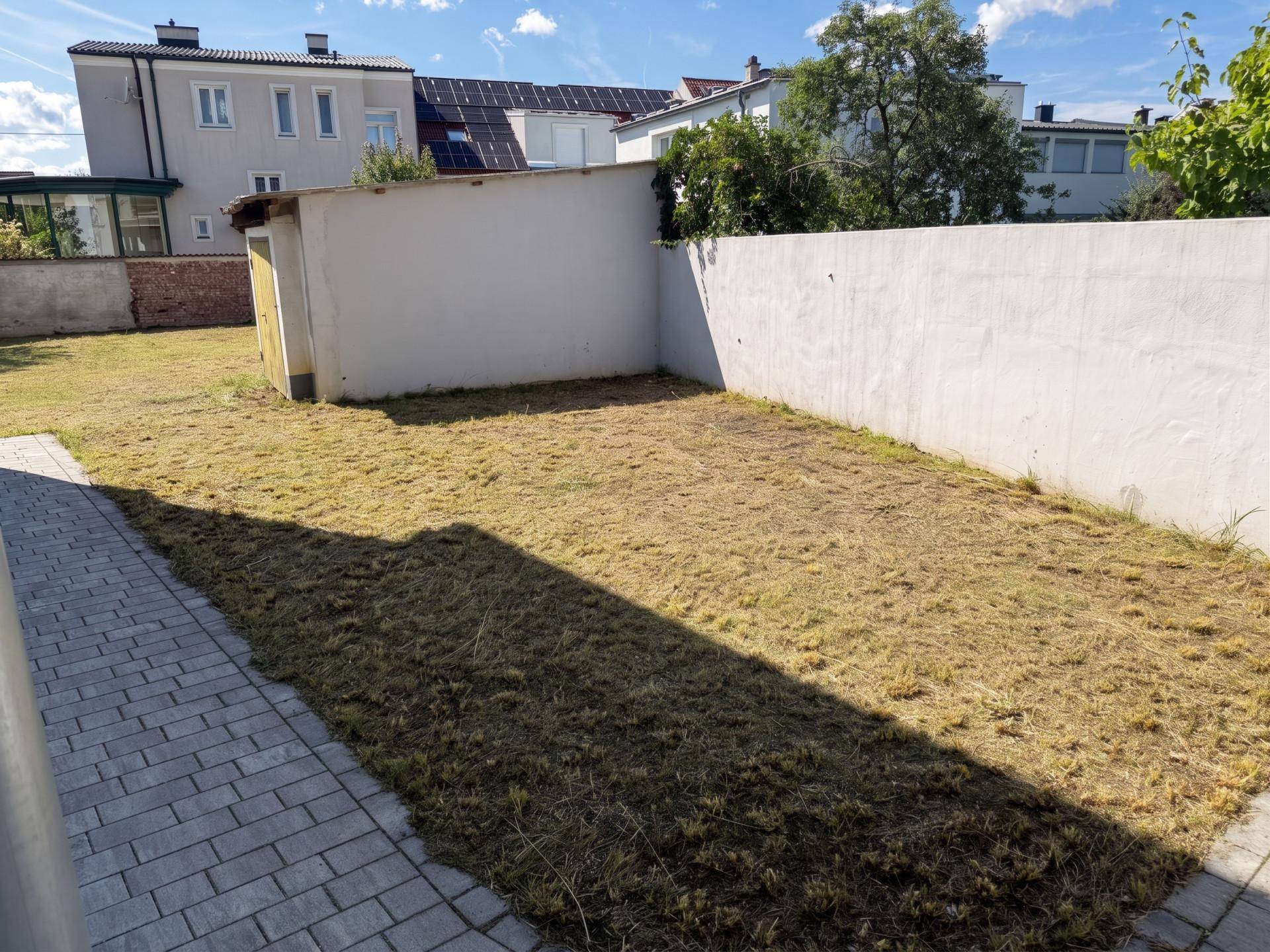 Gepflegter Gartenbereich mit frisch gemähtem Rasen und einer kleinen Gartenhütte.