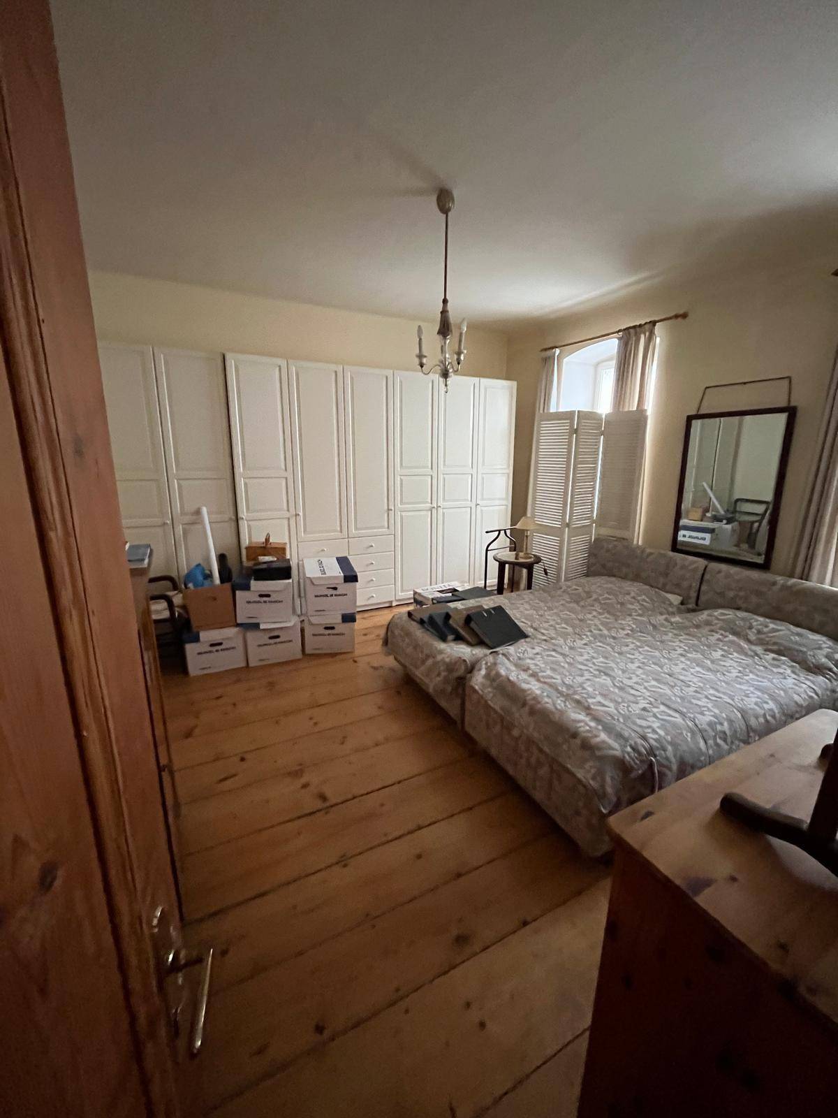 Schlafzimmer mit Holzboden, großen weißen Kleiderschränken und Doppelbett.