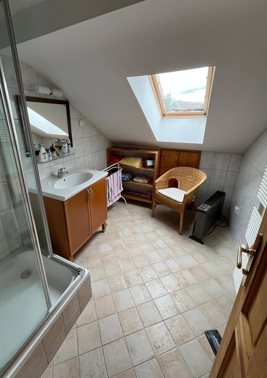 Dachgeschoss-Badezimmer mit Dusche, Waschbecken und Dachfenster für natürliches Licht.