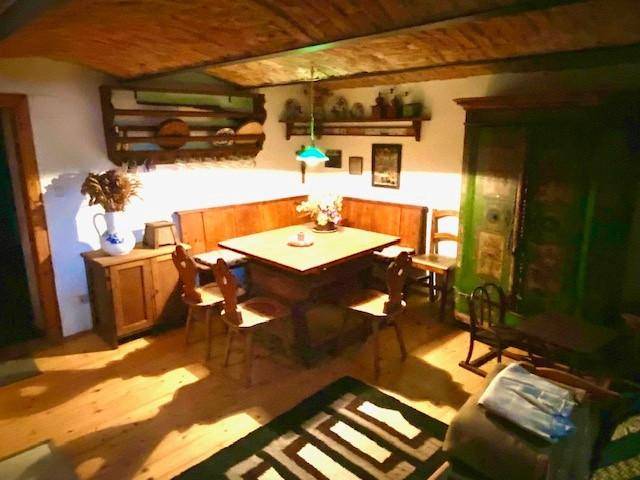Rustikaler Essbereich mit Holztisch, Eckbank und Holzboden unter einer Holzdecke.