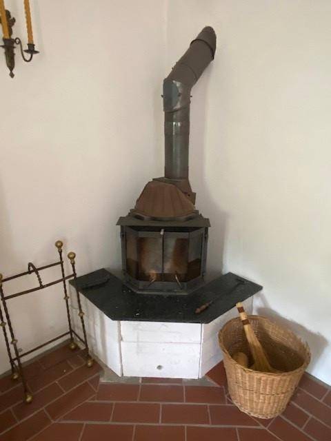 Traditioneller Holzofen mit Kaminrohr und Fliesenboden in einem Wohnbereich.