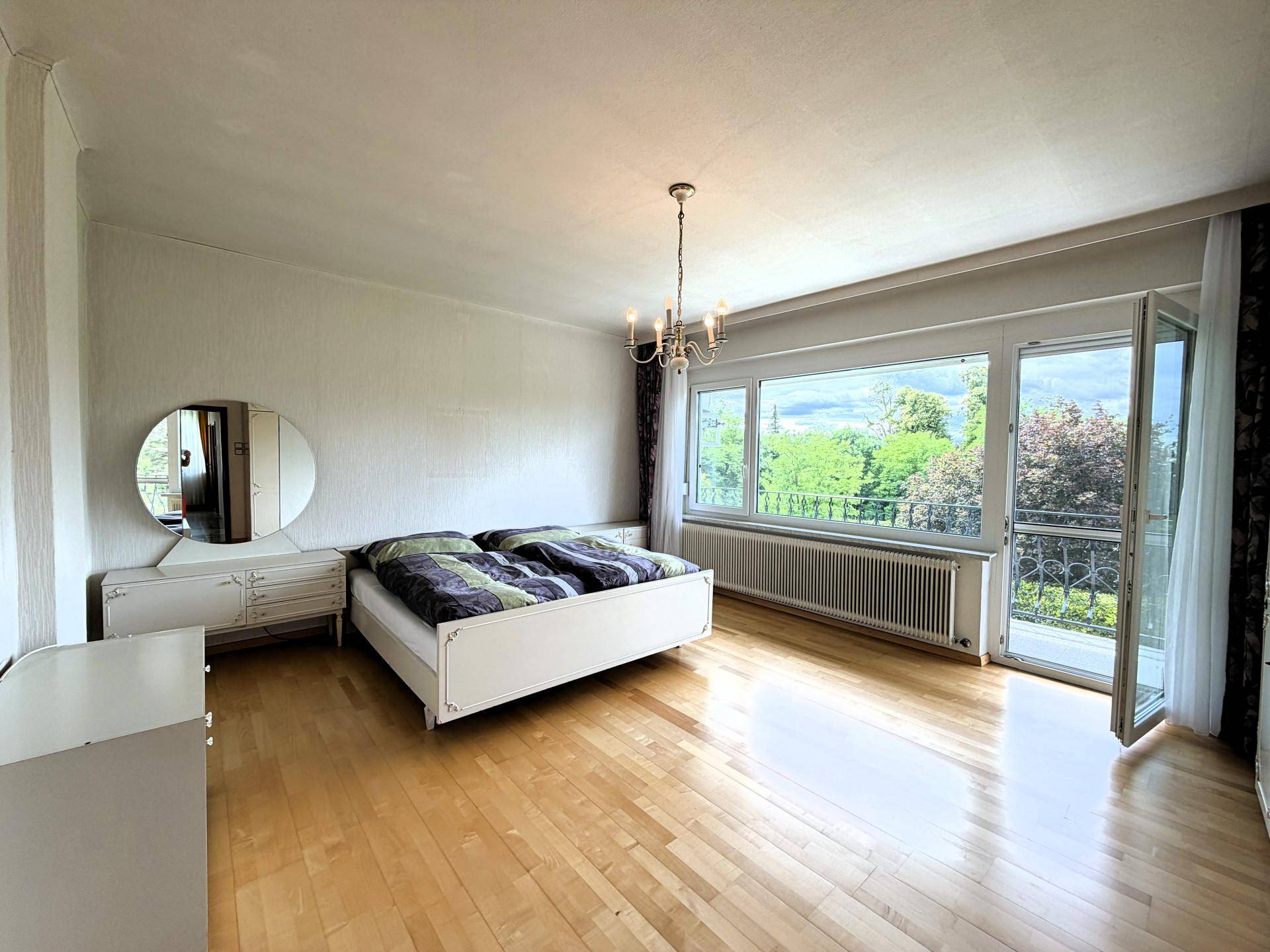 Helles Schlafzimmer mit Doppelbett, Holzfußboden und direktem Zugang zum Balkon.