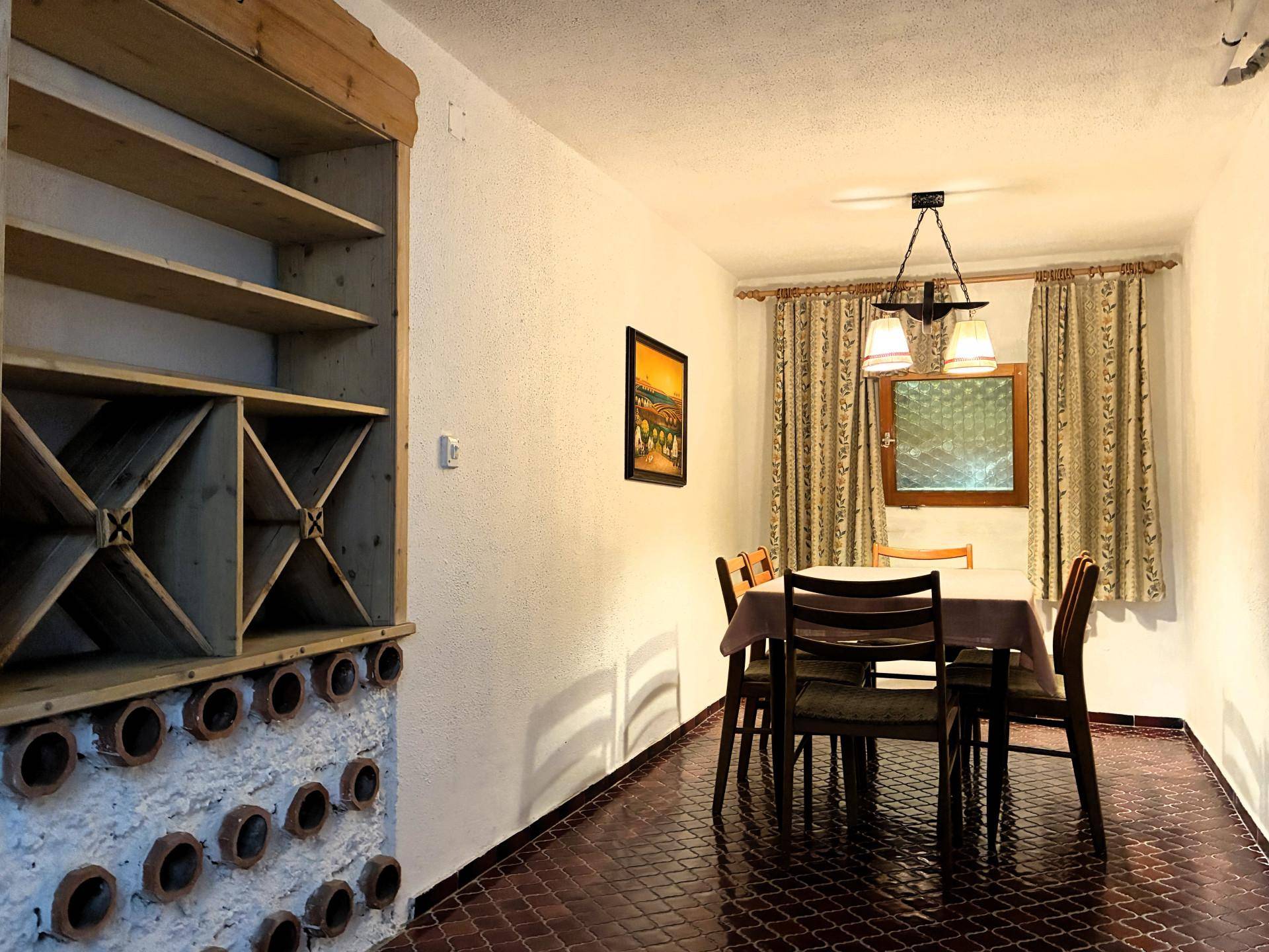 Rustikaler Essbereich im Keller mit integriertem Weinregal und Holztisch.