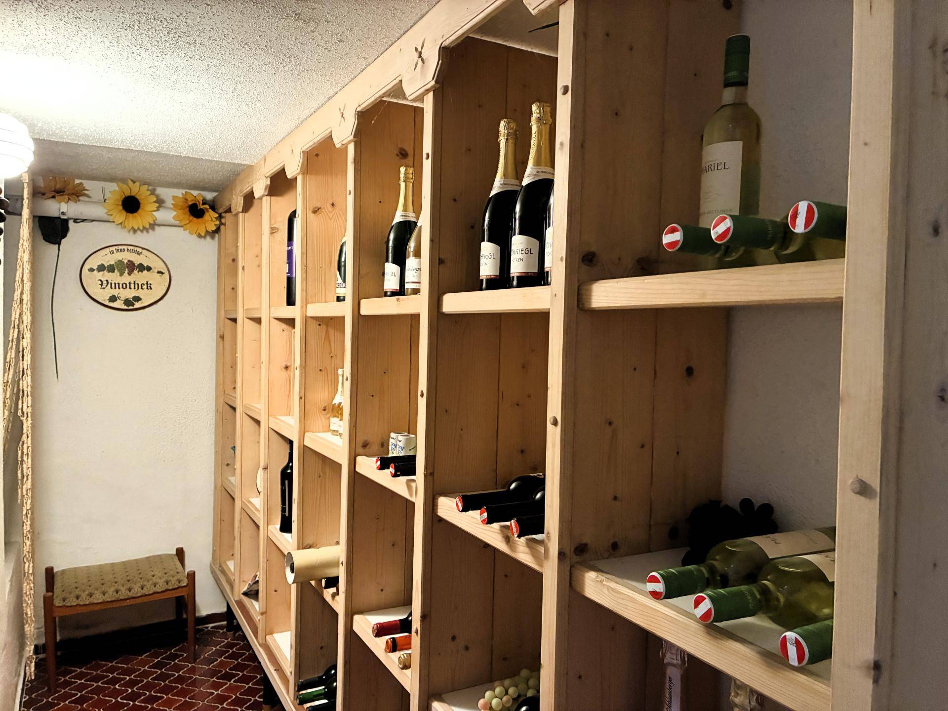 Gut ausgestatteter Weinkeller mit Holzregalen und zahlreichen Weinflaschen.