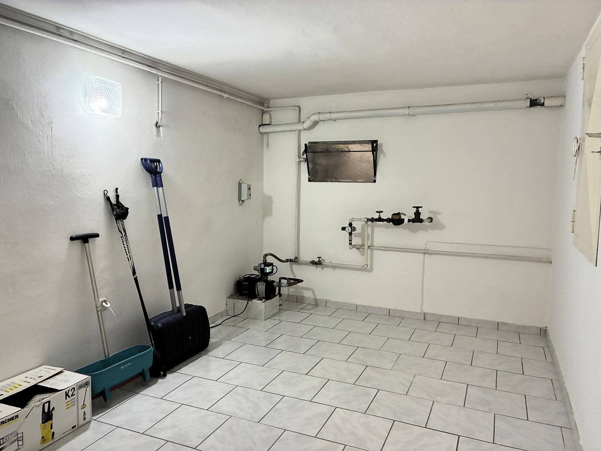 Heller Kellerraum mit Fliesenboden, Wasserleitungen und technischer Ausstattung.
