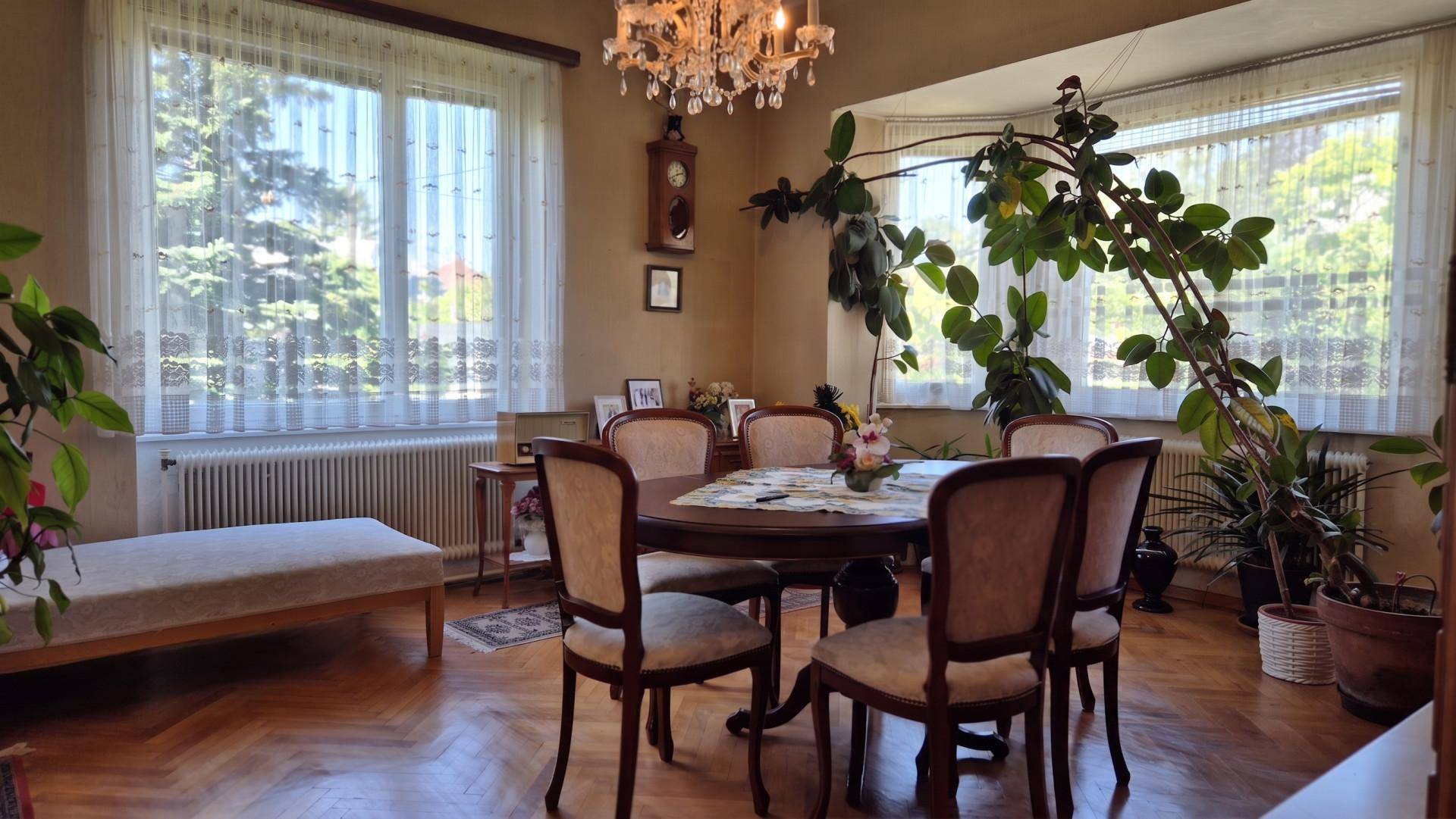Gemütlicher Essbereich mit Holztisch, Stühlen und einem großen Fenster, das viel Tageslicht hereinlässt.