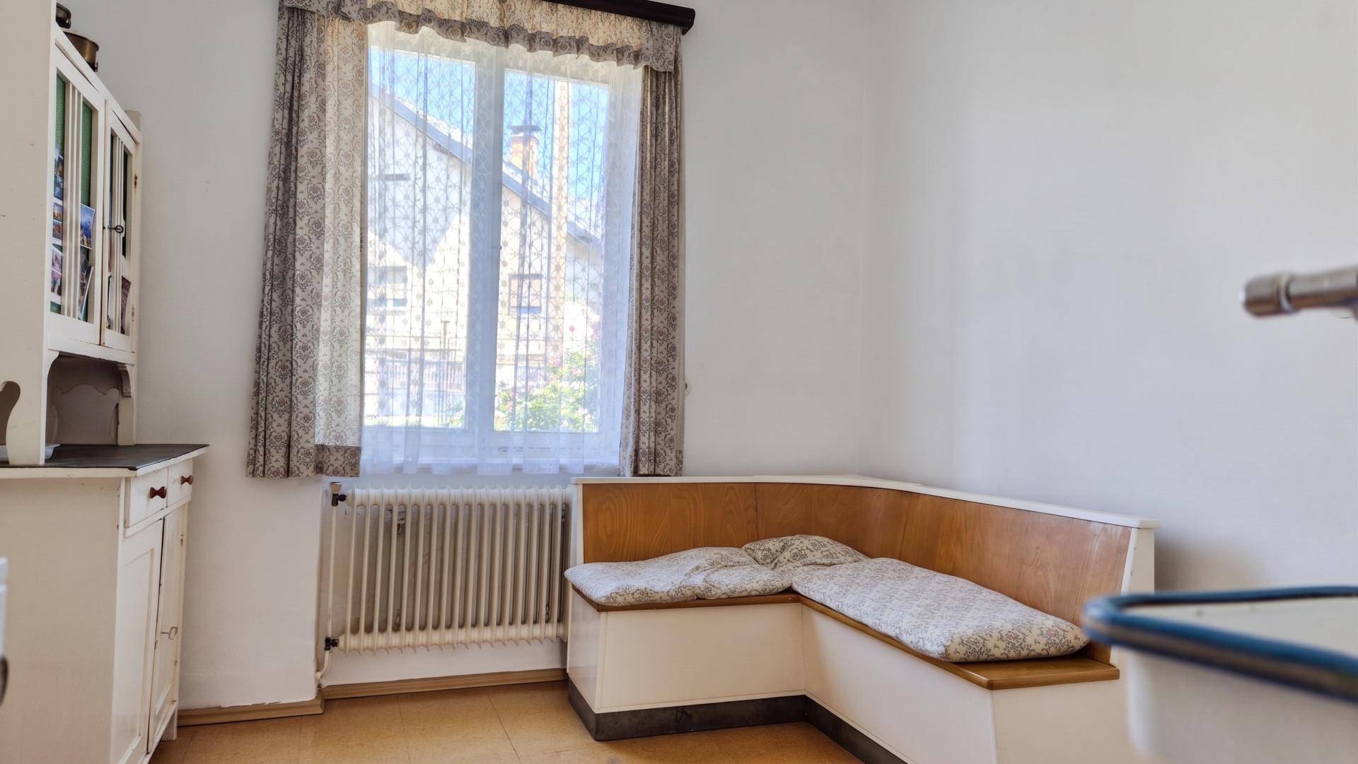 Kleine Küche mit eingebauter Eckbank, Fenster und einem Spülbecken, ideal für eine Essecke.