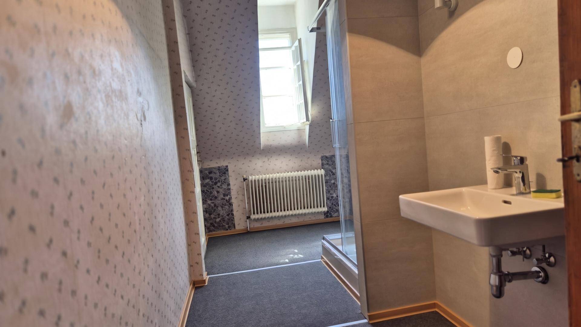Badezimmer mit modernem Waschbecken, Duschkabine und einem Fenster, das Tageslicht spendet.