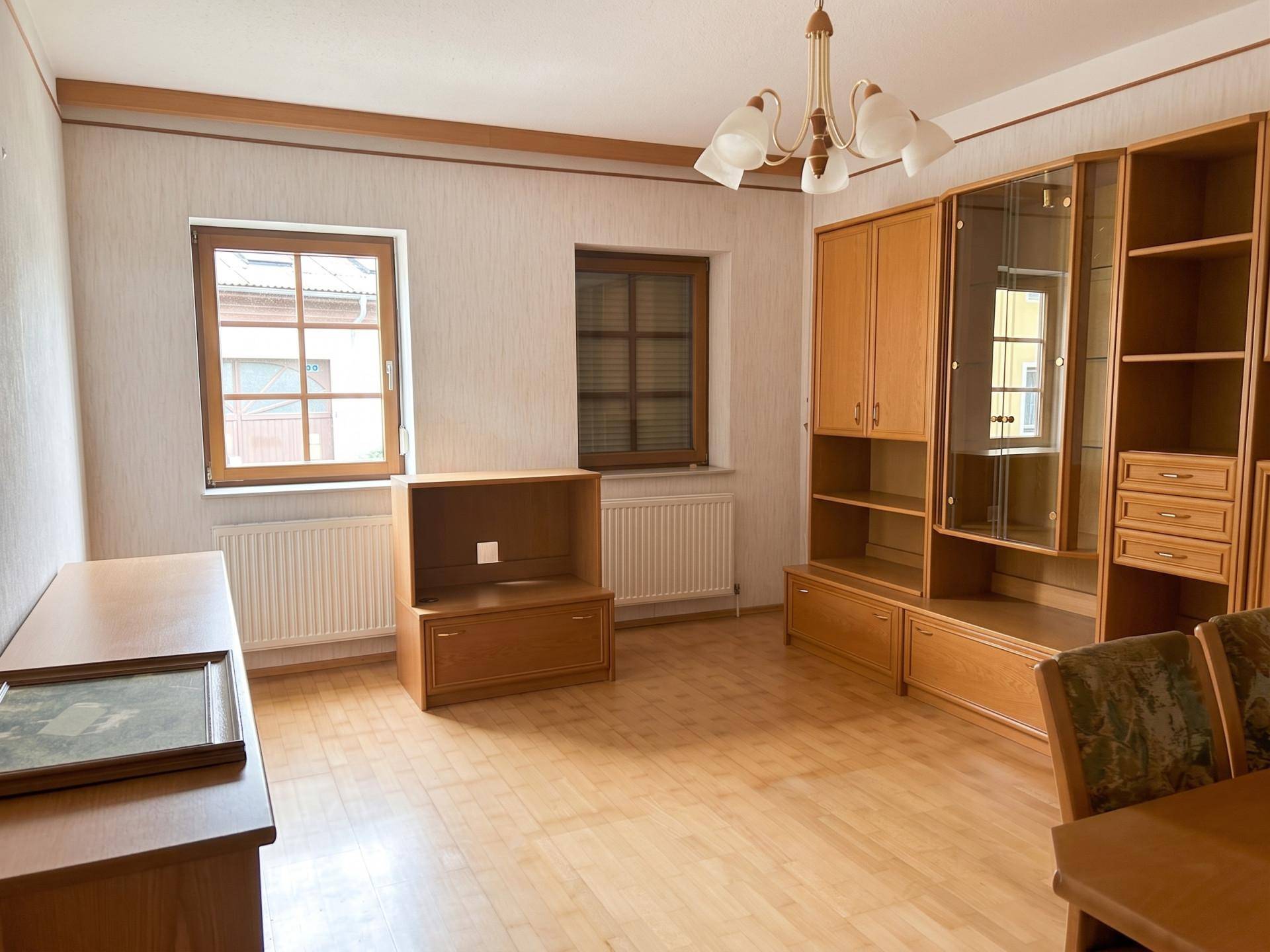 Wohnzimmer mit Holzparkettboden und traditionellen Holzmöbeln, bietet eine gemütliche Atmosphäre.