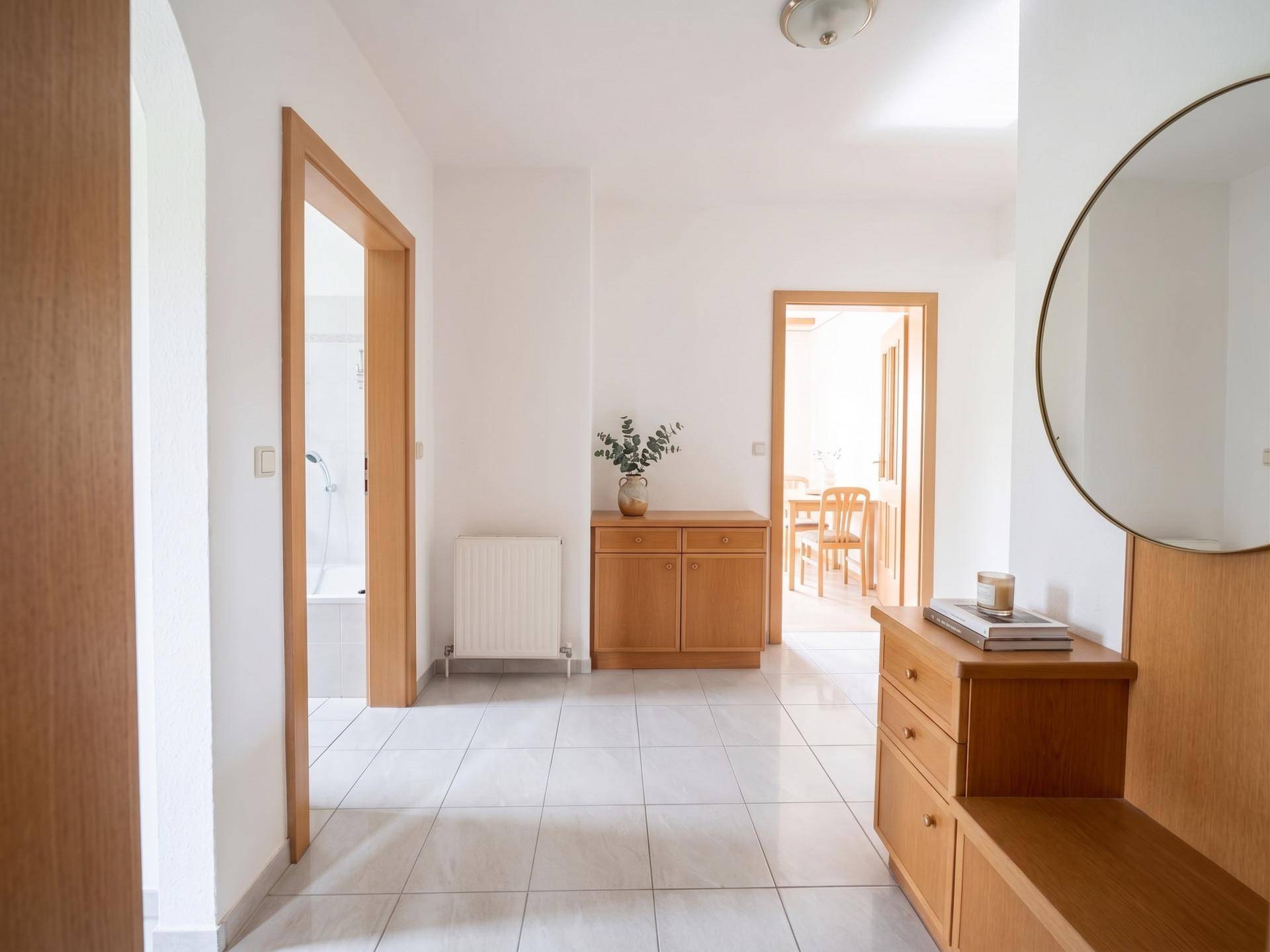 Heller Flur mit Fliesenboden und Holzmöbeln, verbindet die verschiedenen Räume der Wohnung.