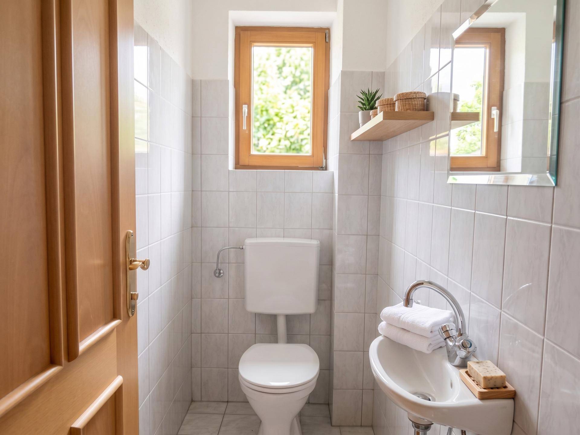 Kleines Gäste-WC mit Fenster, WC und Waschbecken, funktional und hell.