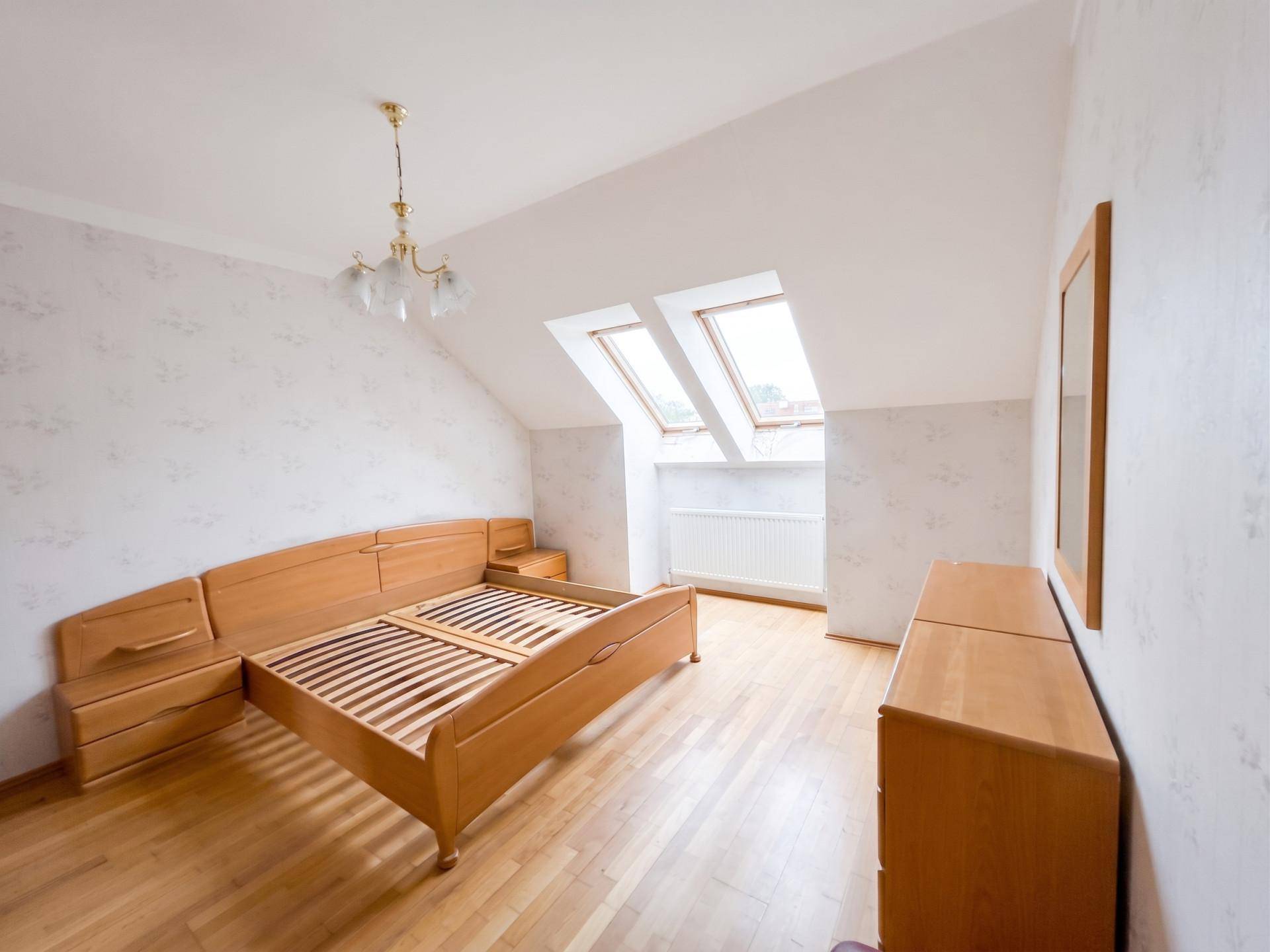 Schlafzimmer im Dachgeschoss mit Holzbett und Dachfenstern, bietet eine helle und gemütliche Atmosphäre.