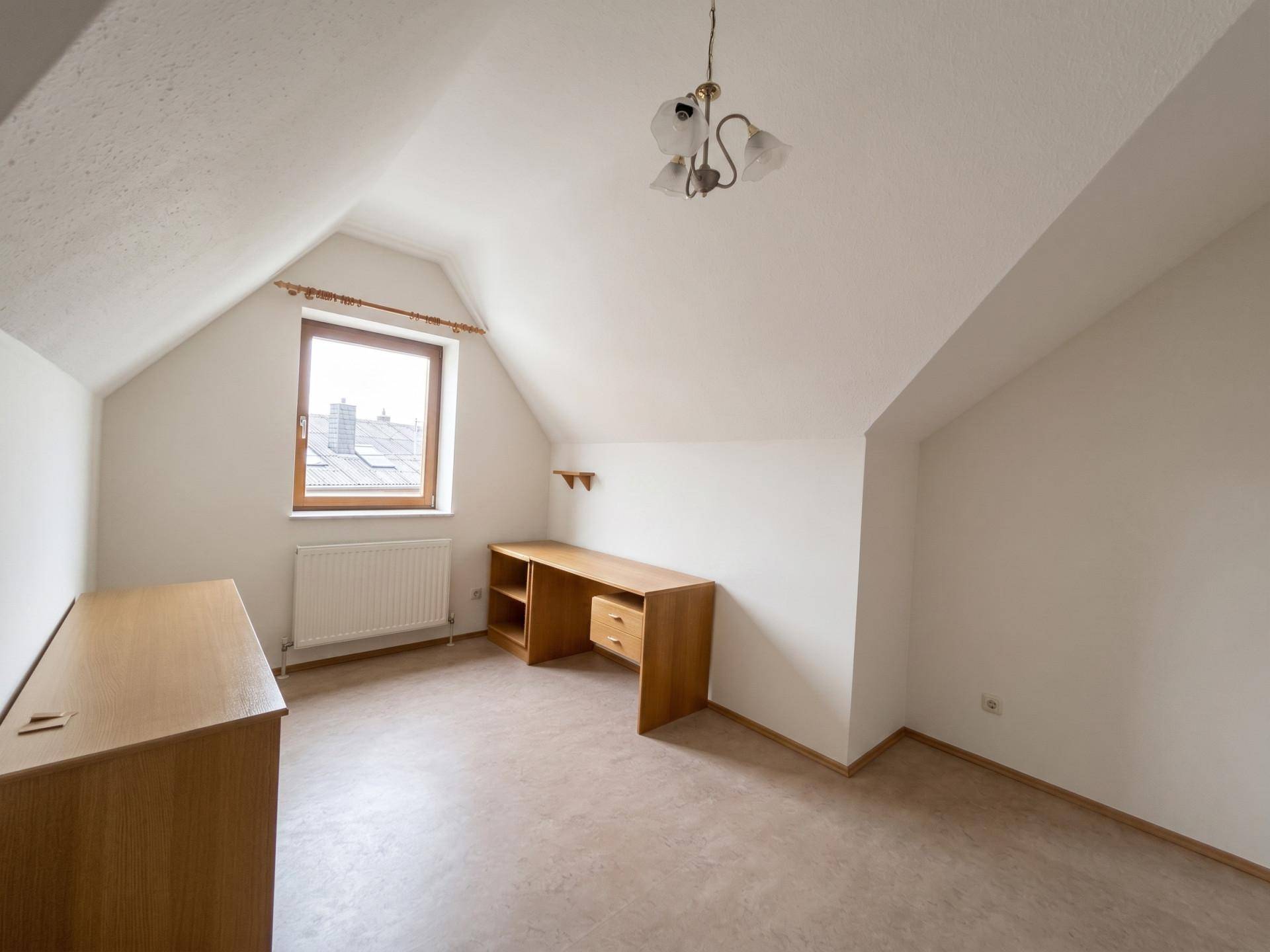 Dachgeschosszimmer mit Schreibtisch und Fenster, ideal als Büro oder Kinderzimmer nutzbar.