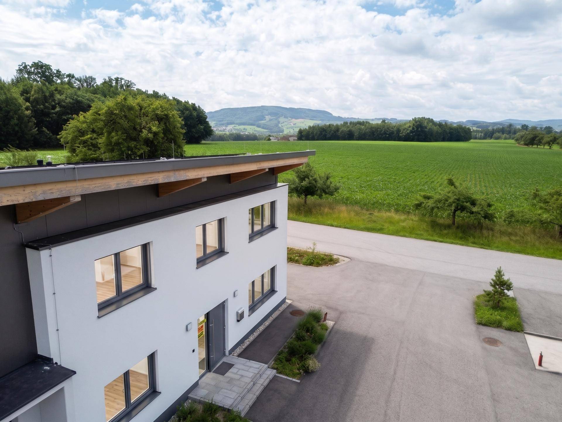 Ansicht des modernen Gebäudeeingangs mit weißer Fassade und umliegenden grünen Feldern.