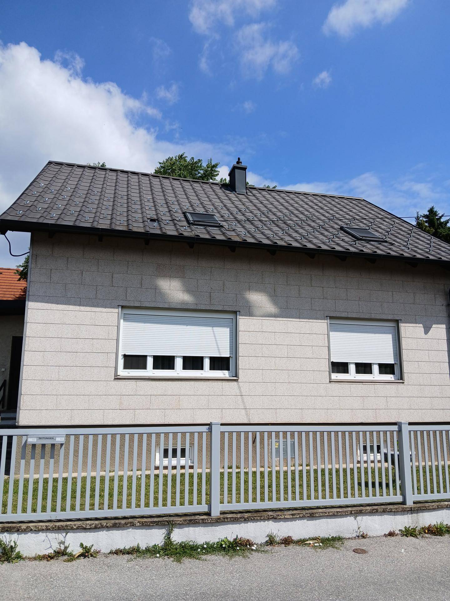 Detailansicht der Hausfassade mit hellen Klinkerriemchen, geschlossenen Rollläden und Satteldach.