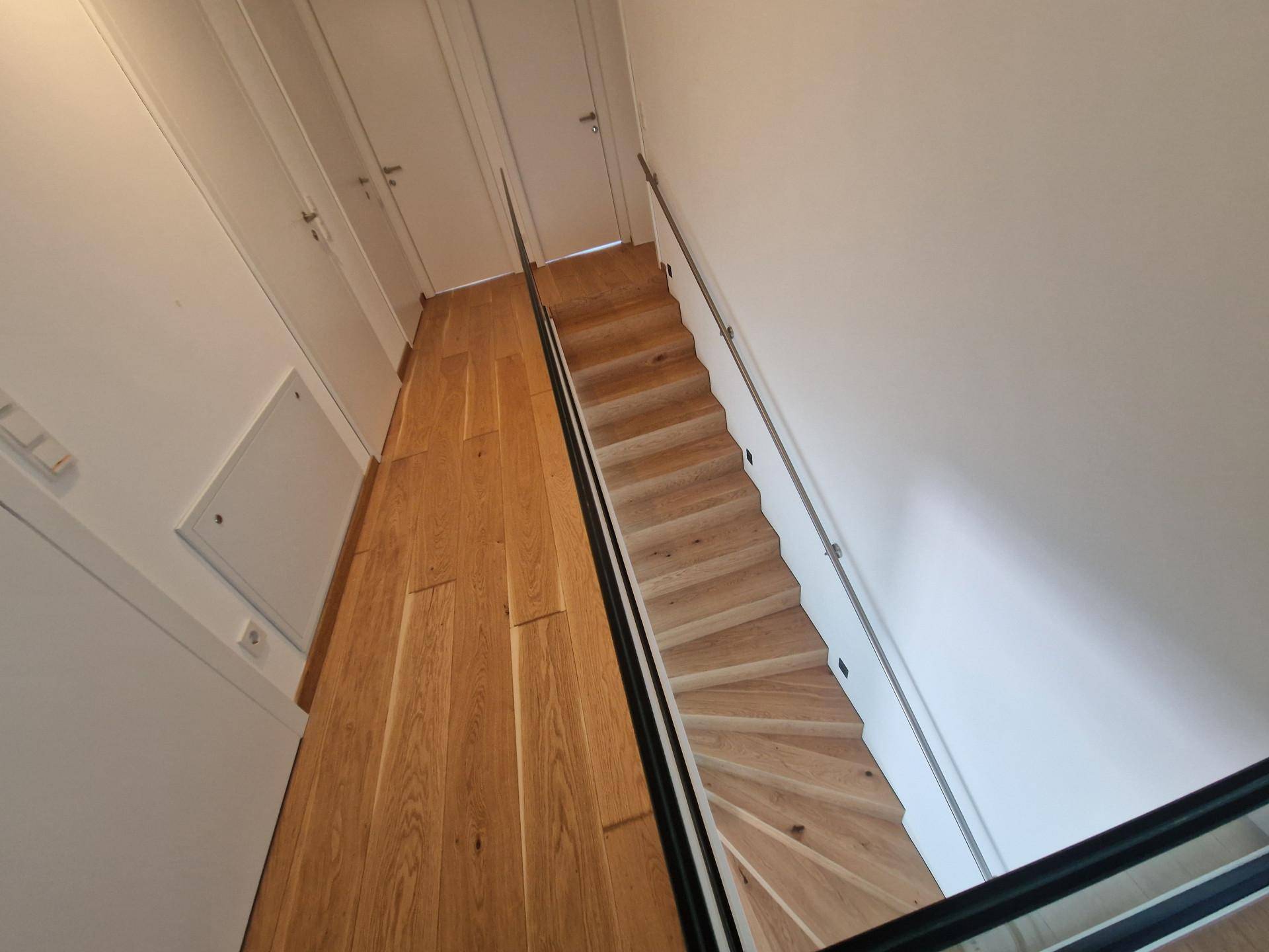 Elegante Holztreppe mit Glasgeländer, die die verschiedenen Ebenen des Hauses verbindet.
