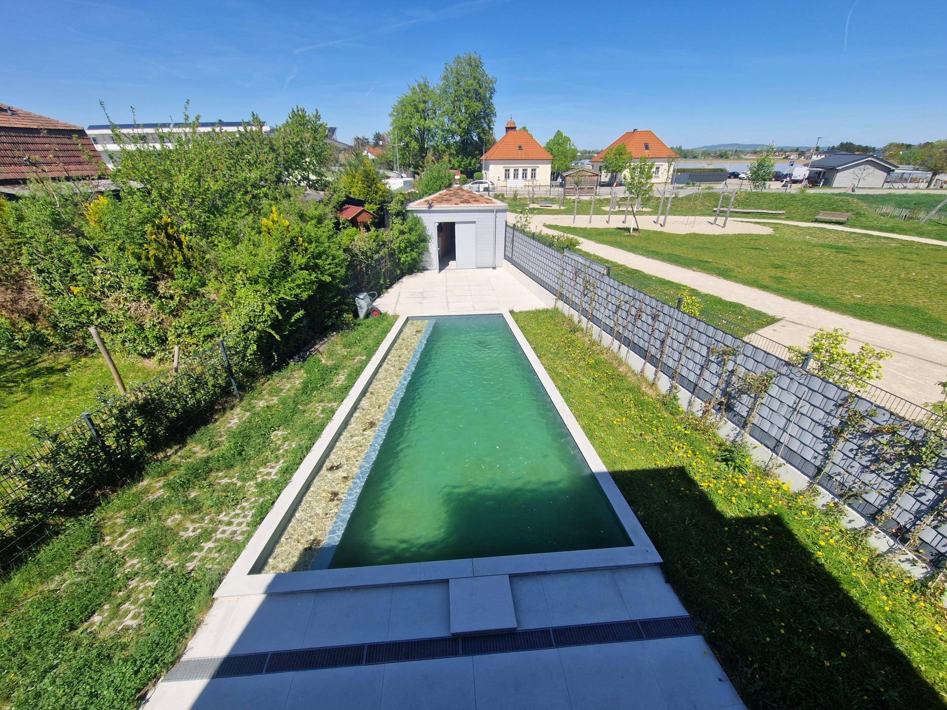 Blick von oben auf den Garten mit Pool, einem kleinen Schuppen und einem angrenzenden Spielplatz.