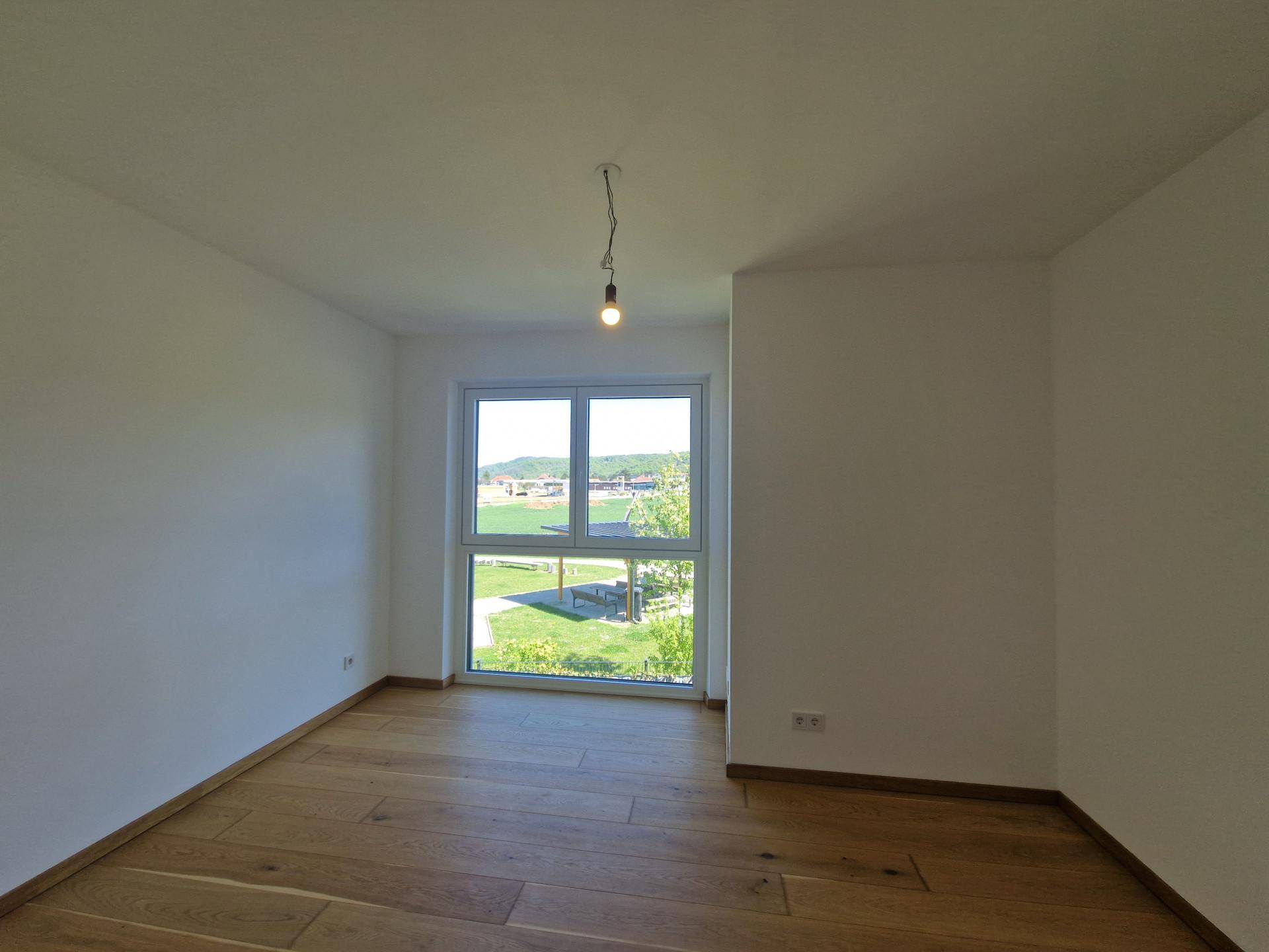 Helles Zimmer mit Holzboden und großem Fenster, das einen weiten Blick auf die Umgebung bietet.