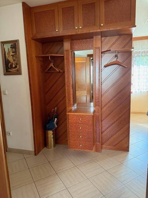 Eingangsbereich mit Einbauschränken aus Holz, Fliesenboden und einem integrierten Spiegel.