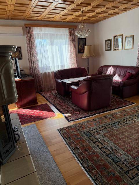 Gemütliches Wohnzimmer mit Ledersofas, Holzboden und einer traditionellen Kassettendecke.