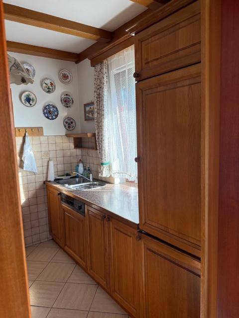 Gemütliche Küche mit Holzschränken, Spülbecken und einem Fenster für natürliches Licht.