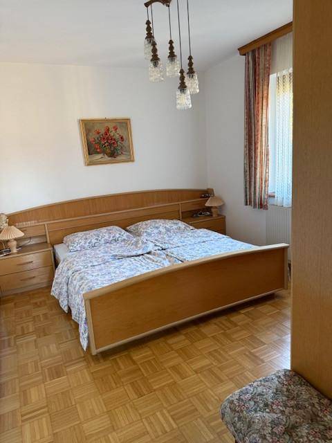 Helles Schlafzimmer mit Doppelbett, Nachttischen und Parkettboden.
