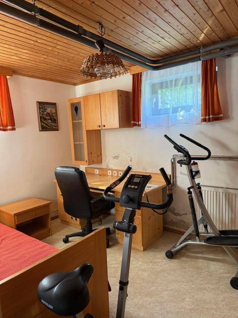 Fitness- und Arbeitsbereich im Keller mit Sportgeräten und Holzdecke.