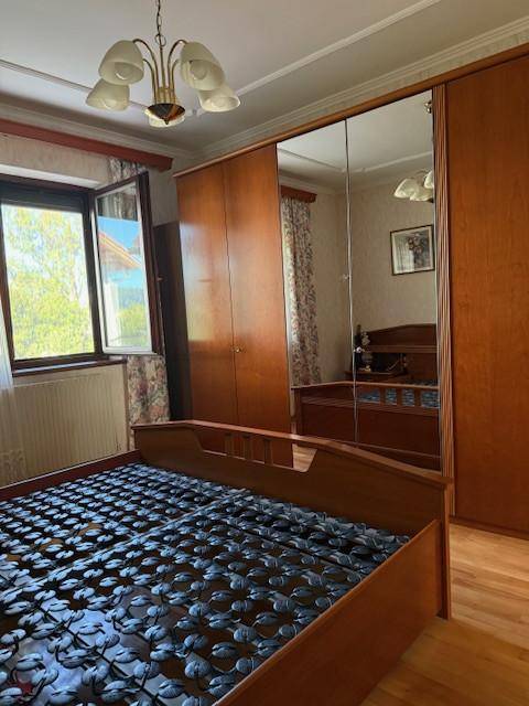 Schlafzimmer mit Doppelbett, Holzschrank mit Spiegeltüren und Parkettboden.