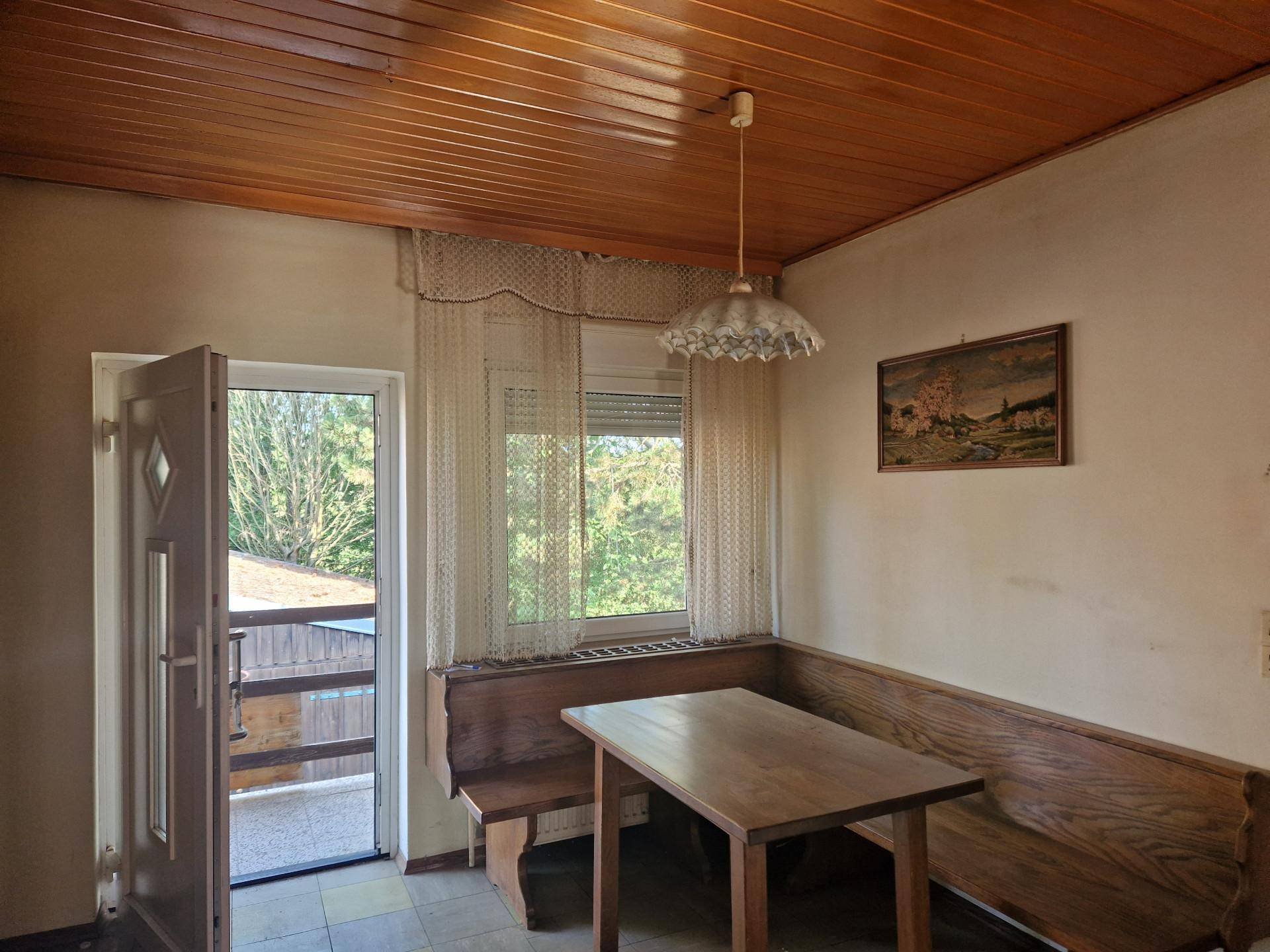 Gemütlicher Essbereich mit Holztäfelung an Decke und Wänden sowie Zugang zum Balkon.