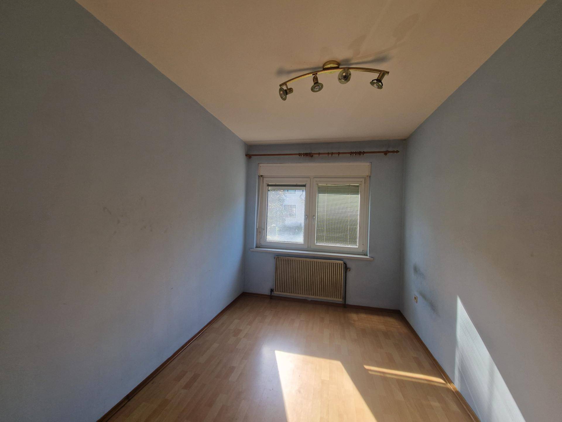 Leeres Zimmer mit blauen Wänden, Holzfußboden und Fenster.