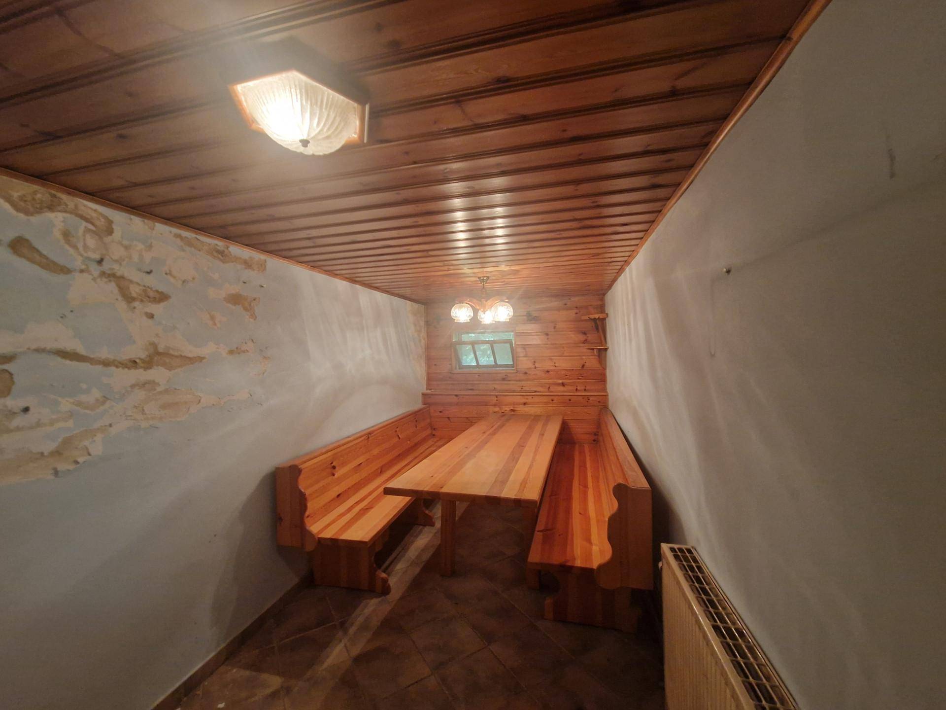 Traditioneller Essbereich mit Holztisch und Bänken sowie Holzvertäfelung.