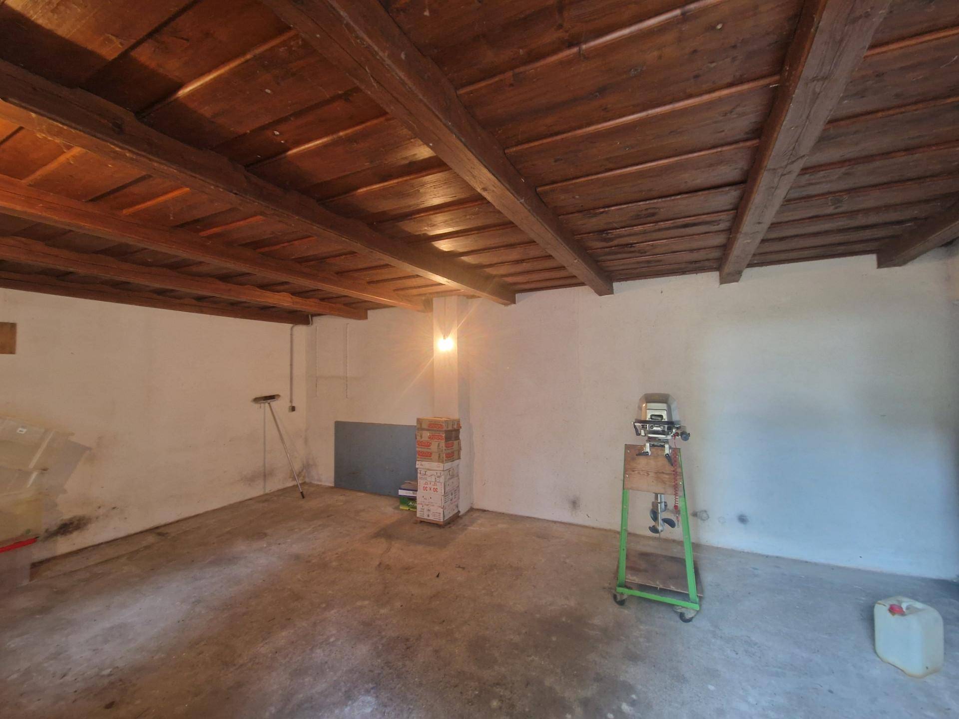 Kellerraum mit sichtbaren Holzbalken an der Decke und Betonboden.