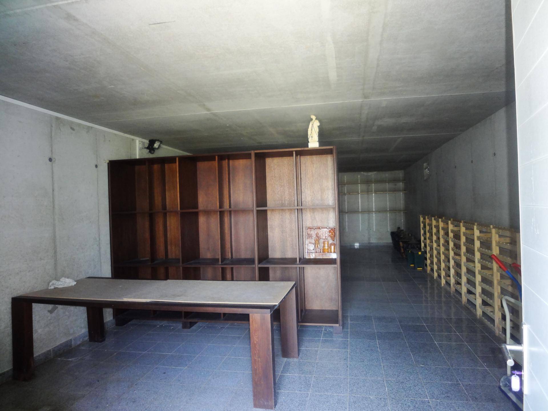 Langer Kellerraum mit Betonwänden, Fliesenboden und Holzregalen für Lagerung.