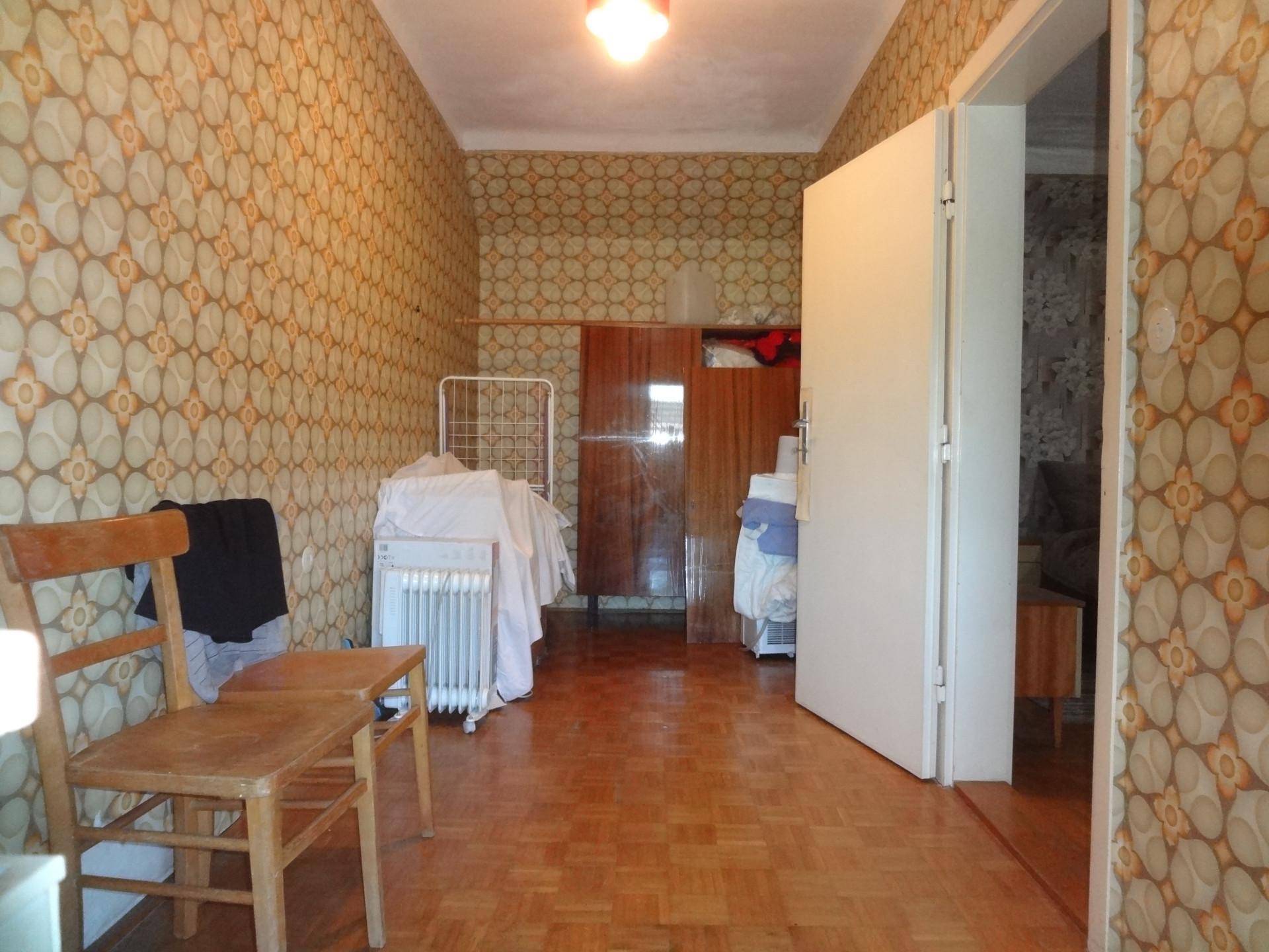 Schlafzimmer mit gemusterter Tapete, Parkettboden und Holzschrank im traditionellen Stil.