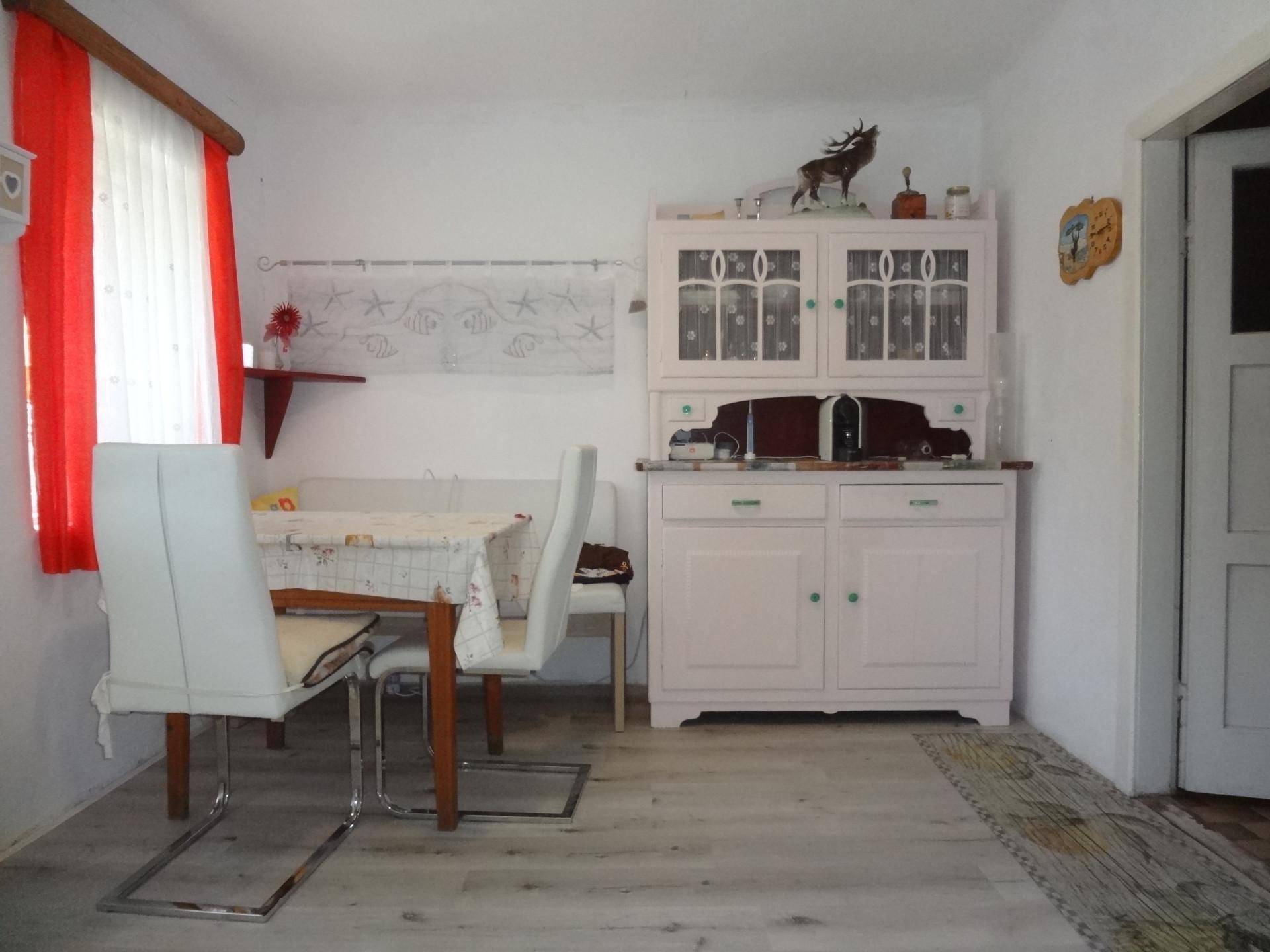 Esszimmer mit weißem Esstisch, Stühlen und einem traditionellen Buffetschrank.