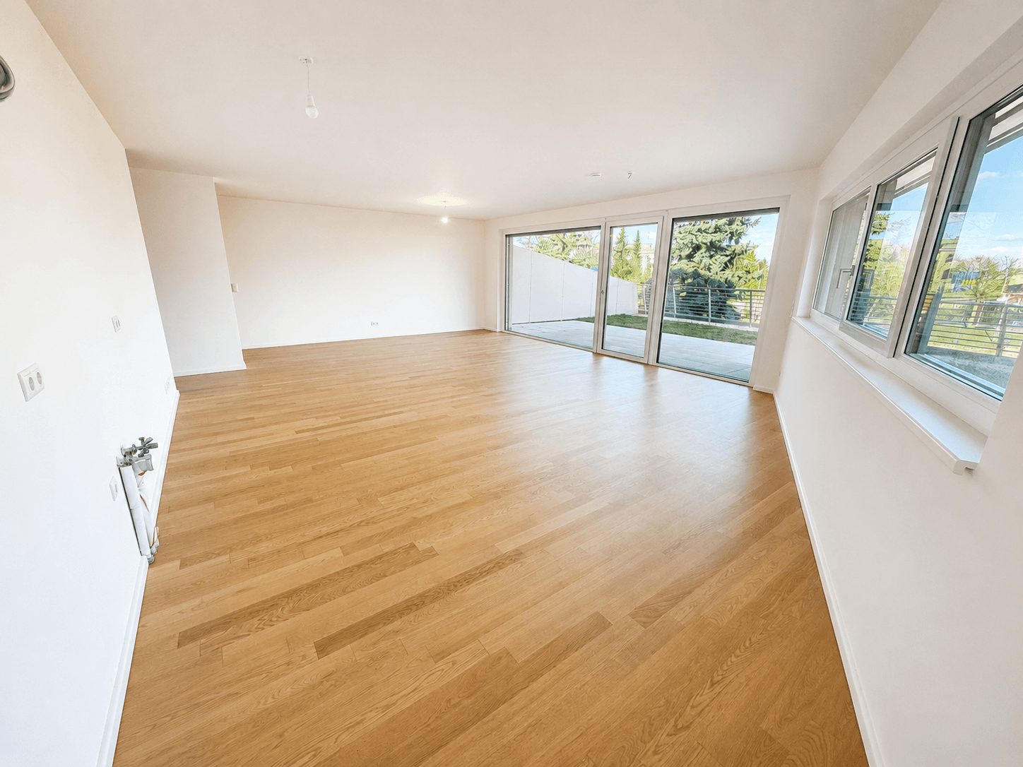 Geräumiger, heller Wohnbereich mit großen Fenstern und direktem Zugang zum Garten.