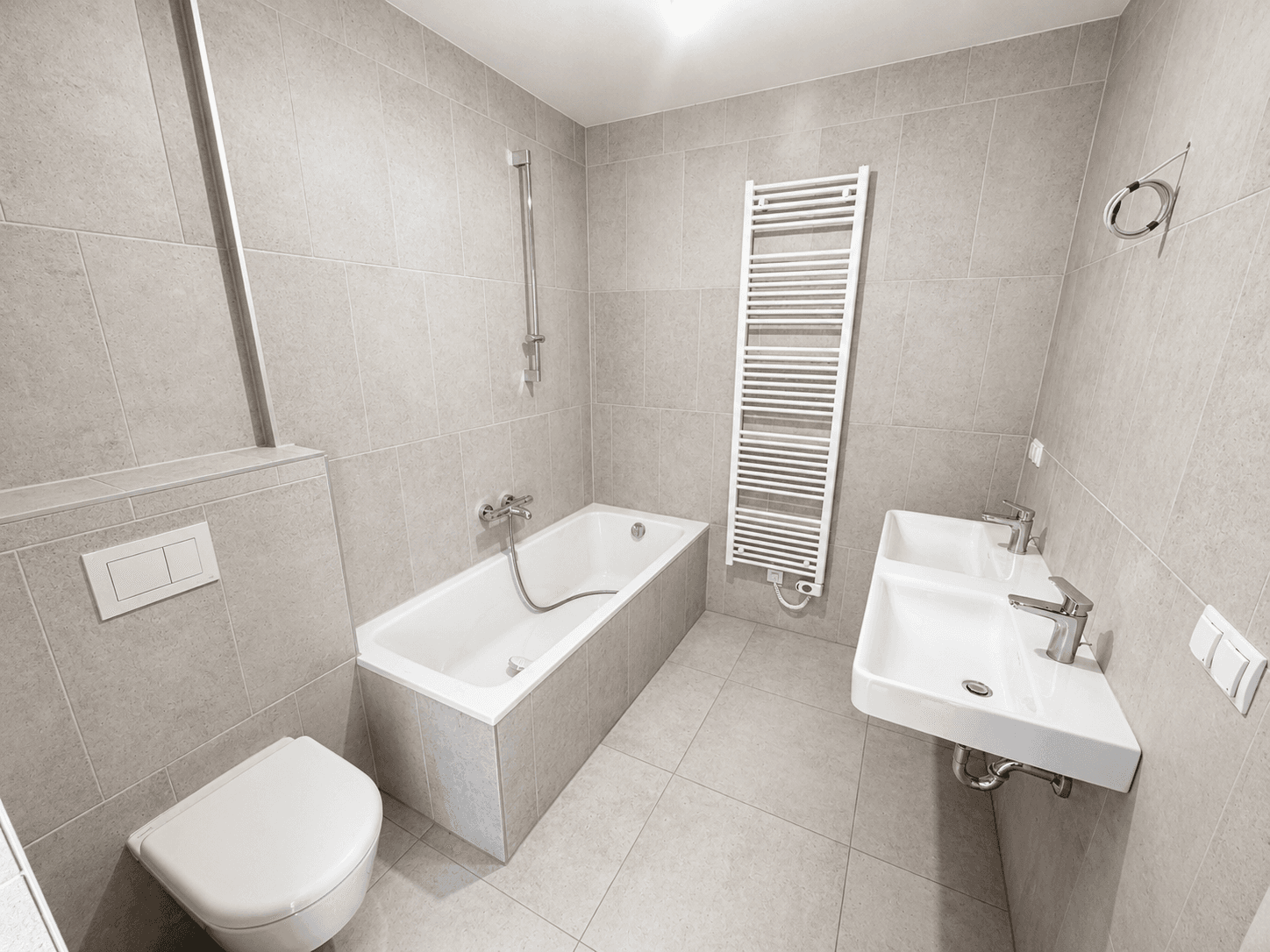 Elegantes Badezimmer mit Badewanne, Doppelwaschbecken, Wand-WC und beheiztem Handtuchhalter.