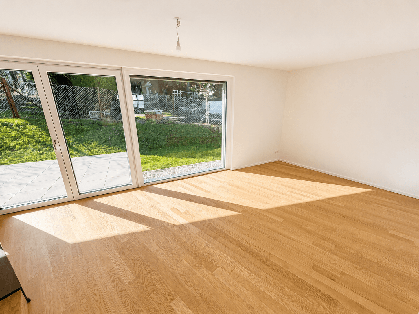 Lichtdurchfluteter Raum mit Eichenparkett und direktem Zugang zur Terrasse und zum Garten.
